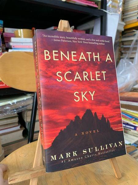 Beneath a Scarlet Sky novel by Mark Sullivan, displayed on wooden stand amid bookshelves